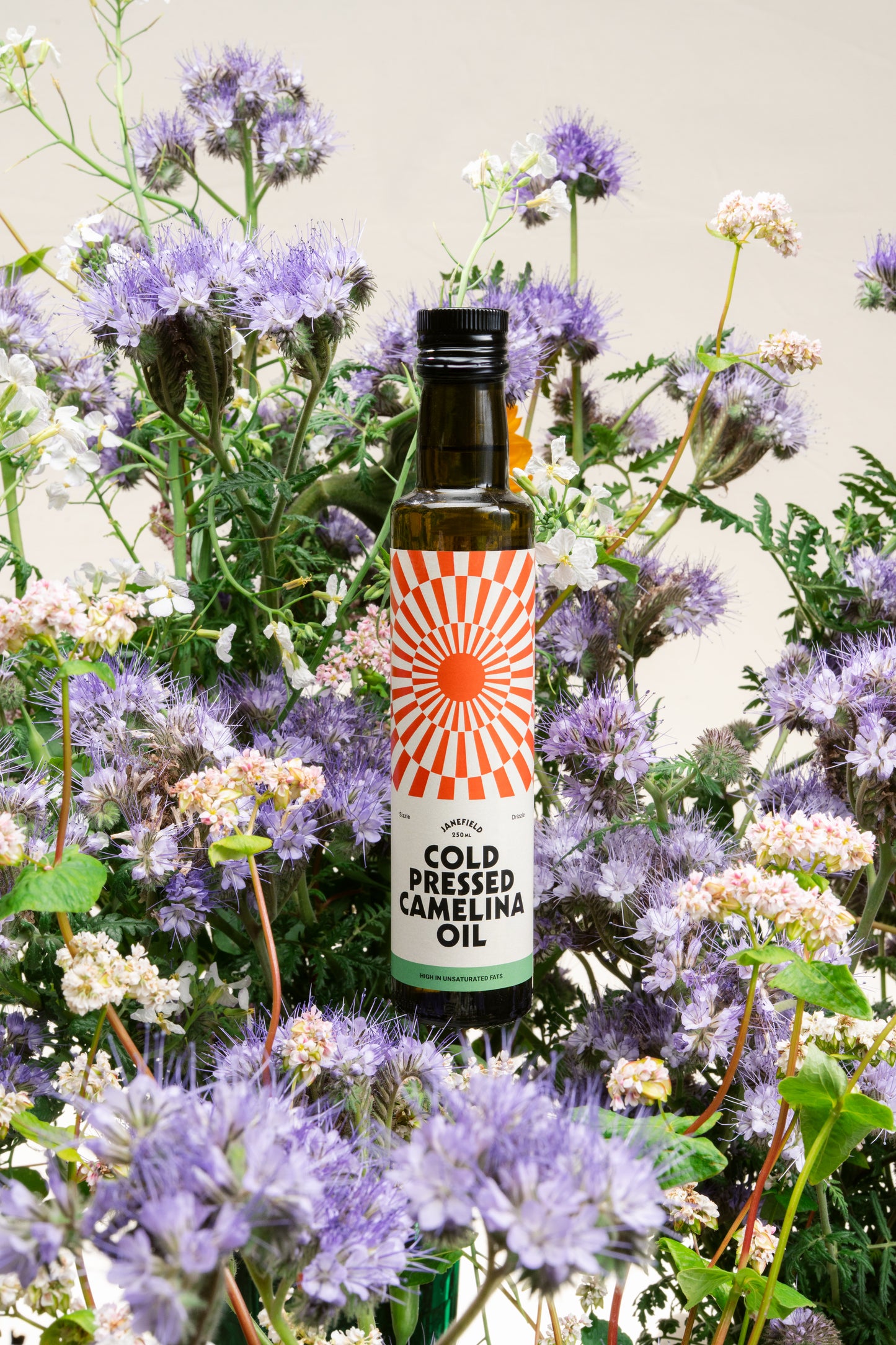 Camelina oil bottle amongst fresh meadow flowers from the farm