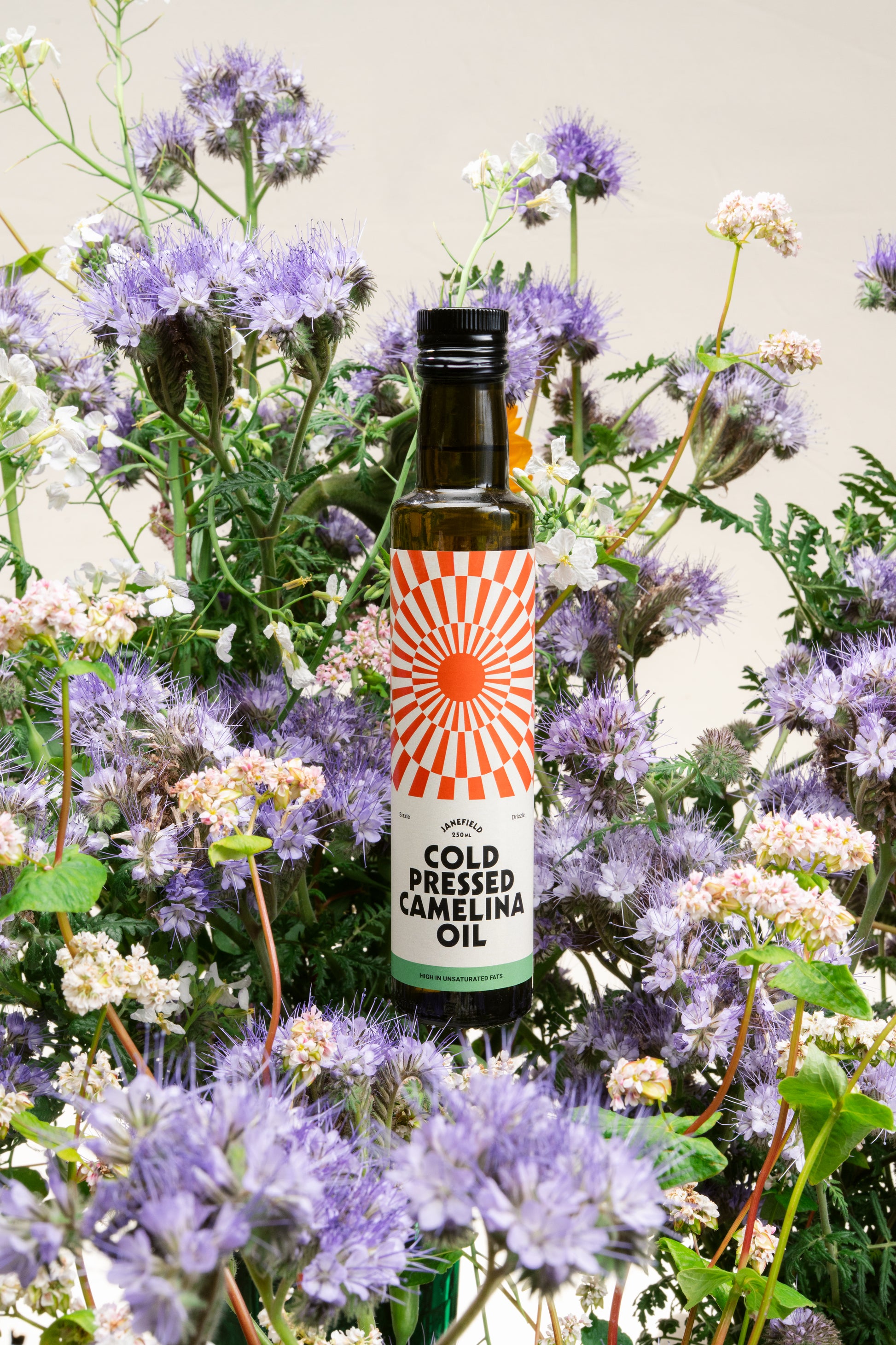 Camelina oil bottle amongst fresh meadow flowers from the farm